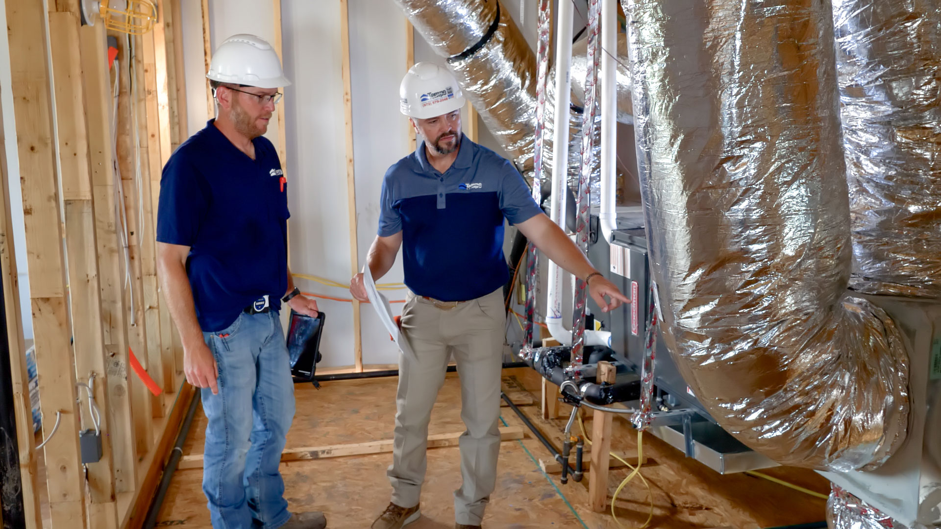 alt="Photo with two Tempo Air New HVAC Construction Experts, in a attic during the process of construction of a new house, near by an HVAC system unit, inspecting installation."