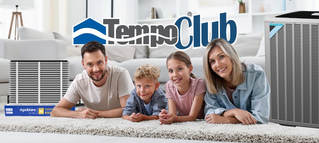alt="Happy family posing on floor at home with an AprilAire Air Filter and a Daikin Condenser, possing for Tempo Club Membership from Tempo Air, heating, cooling and plumbing services."