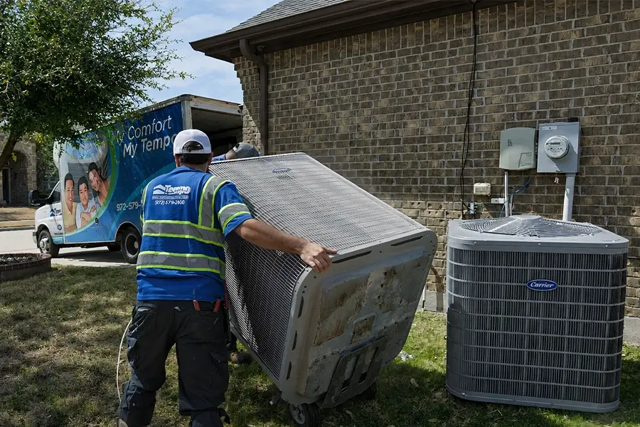 Two HVAC technicians from Tempo are replacing an outdoor condensing unit at a customer's home.