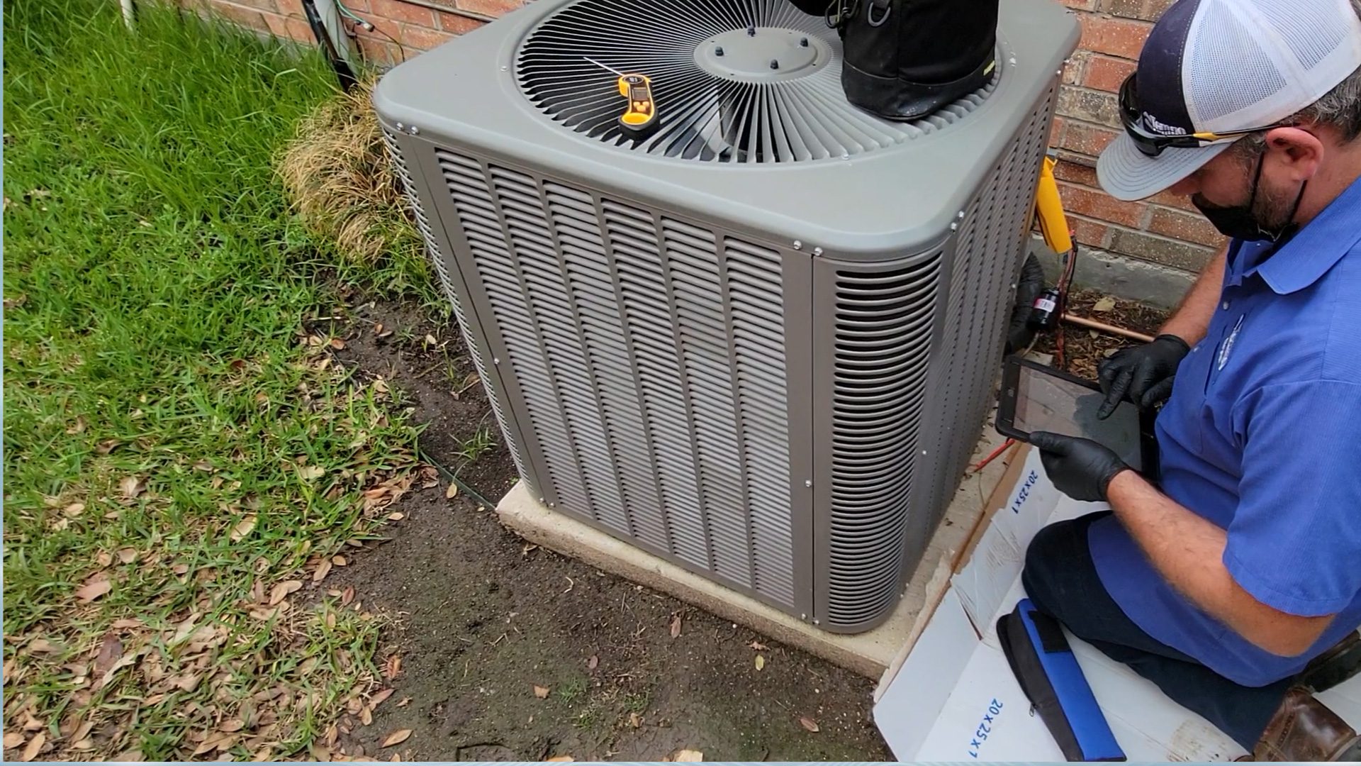 alt="Tempo Air Expert HVAC Technician during an inspection of a condenser unit in a backyard."