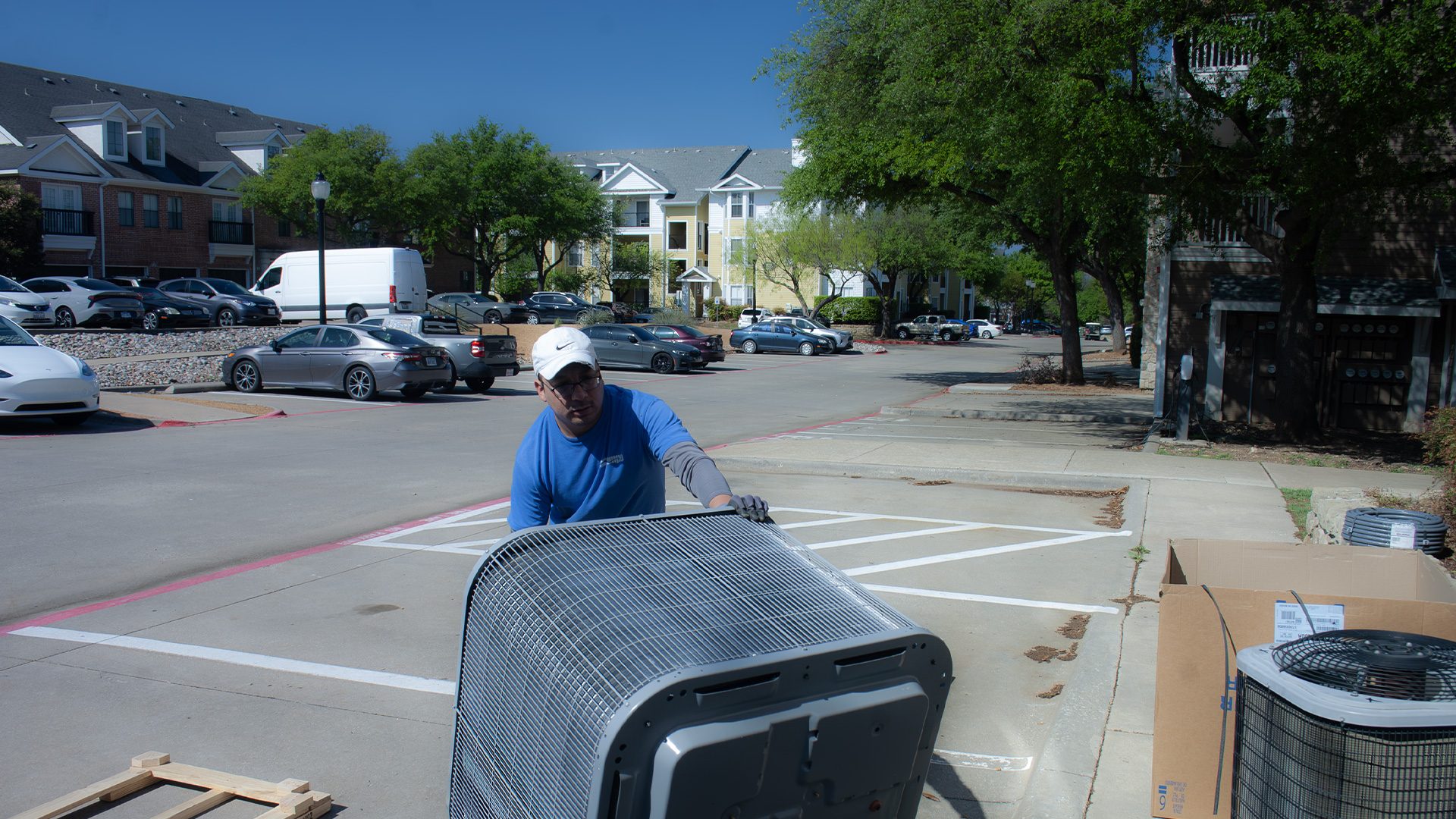 alt="Tempo Air Multifamily Technician moving a new HVAC condenser in an Apartment Complex."